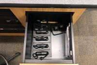 Pedestal - inside view of drawer showing two wireless mics in charging base and assistive listening devices in charger