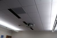 White 2¿ x 2¿ tile mounted in the ceiling to provide microphone coverage over student seating