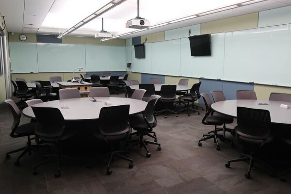 View of room showing of student group table and chair seating, markerboards, and display monitors on walls