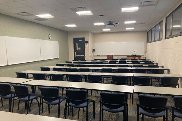 Front of room view with lectern on right in front of markerboard and exit door on left