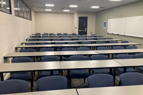 Back of room view of student table and chair seating and exit doors at right rear of room