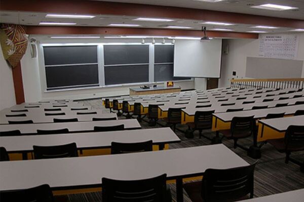 Front of room view with lectern center in front of chalkboards and projection screen lowered on the right