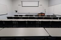 Front of room view with lectern on right in front of markerboard and projection screen partially raised