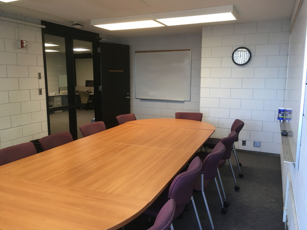 Photo of back of room from front of room with conference room table seating.