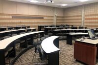 Back of room view of student tiered fixed-table and chairs seating 