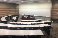 Front of room view with lectern center in front of markerboard and projection screen lowered