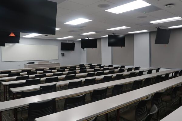 Front of room view with lectern center in front of markerboard and display monitors left and right