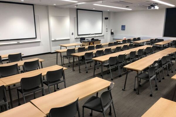 Front of room view with lectern in center front of room and projection screens lowered