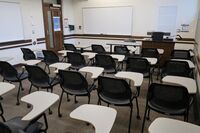 Front of room view with lectern on right in front of markerboard and  exit door on front left wall