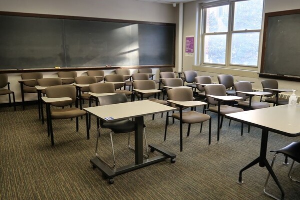 Rear of room view of student tablet arm chair seating and chalkboard in rear of room and right side of room