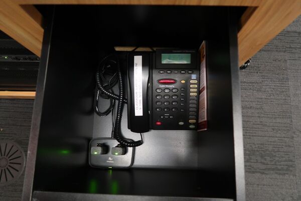 Pedestal - inside view of drawer showing two wireless mics in charging base and telephone