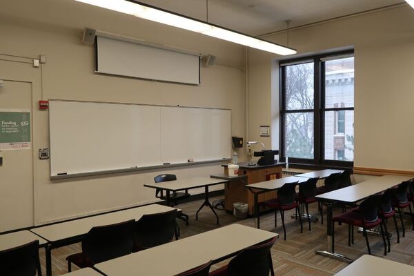 Front of room view with lectern on right side and projection screen partially lowered