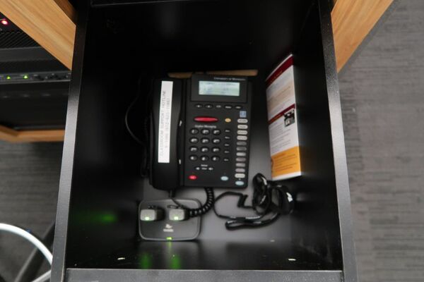 Pedestal - inside view of drawer showing two wireless mics in charging base and telephone