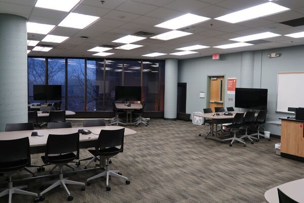 View of room of student student group seating and  exit door at right rear of room