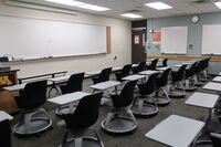 Front of room view with lectern on left in front of markerboard, exit door on right