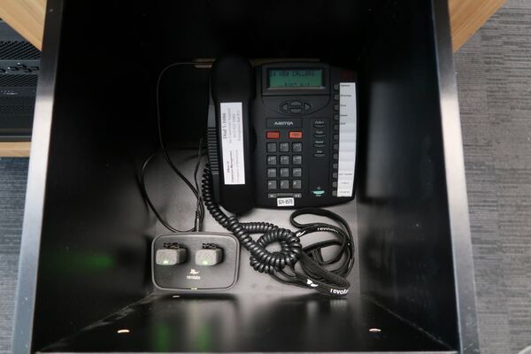 Pedestal - inside view of drawer showing two wireless mics in charging base and telephone