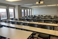 Back of room view of student table and chair seating and markerboard on rear wall