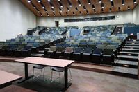 Back of room view of student auditorium seating and three exits at rear of room