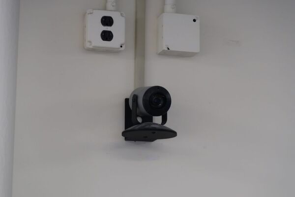 Camera mounted to a wall and instructor enabled adjustments to the lens to allow the instructor to be "seen" by the camera in more locations around the room