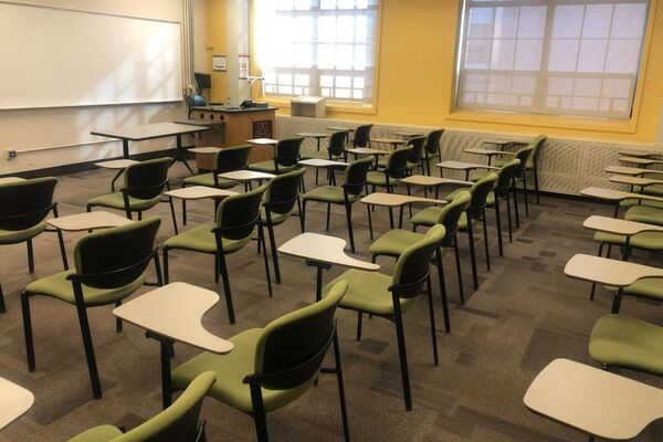 Front of room view with lectern on left in front of markerboard and projection screen lowered