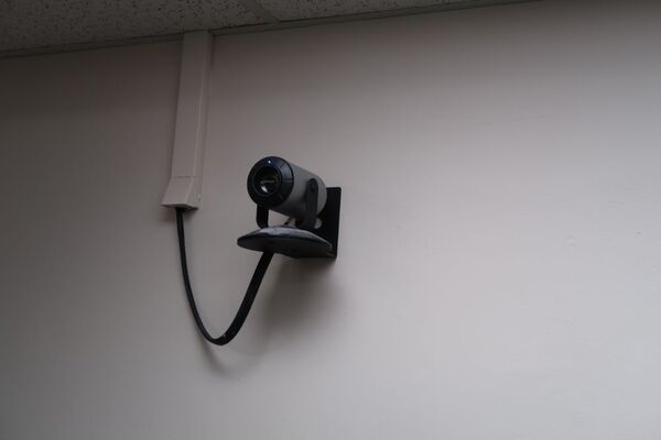 Camera mounted to a wall and instructor enabled adjustments to the lens to allow the instructor to be "seen" by the camera in more locations around the room