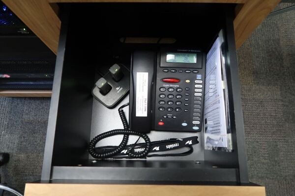 Pedestal - inside view of drawer showing two wireless mics in charging base and phone