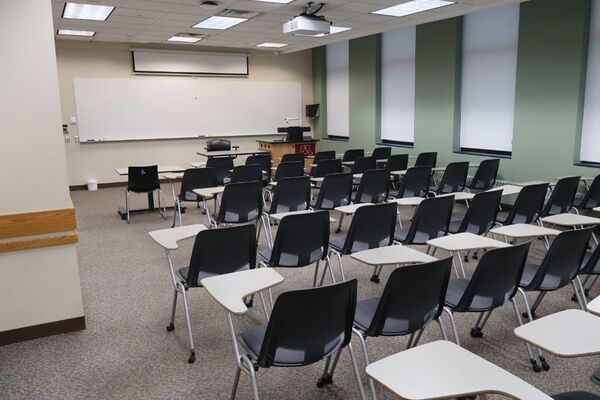 Front of room view with lectern on right in front of markerboard and projection screen partially raised