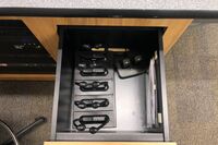 Pedestal - inside view of drawer showing two wireless mics in charging base and assistive listening devices in charger