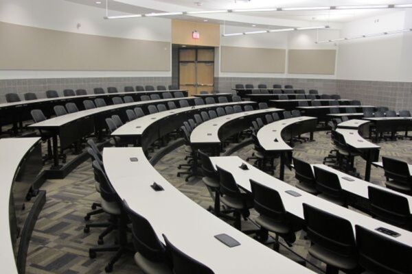 Back of room view of student tiered fixed-table and chair seating and  exit door at rear of room