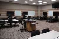 Back of room view of student collaborative table and chair seating and student displays and markerboards on side walls