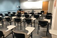 Front of room view with lectern on left in front of markerboard and projection screen partially lowered