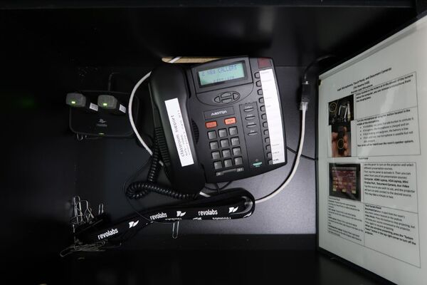 Pedestal - inside view of drawer showing two wireless mics in charging base and telephone