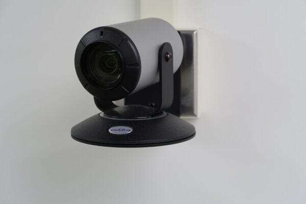 Camera mounted to a wall and instructor enabled adjustments to the lens to allow the instructor to be "seen" by the camera in more locations around the room