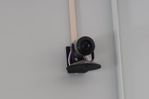 Camera mounted to a wall and instructor enabled adjustments to the lens to allow the instructor to be "seen" by the camera in more locations around the room