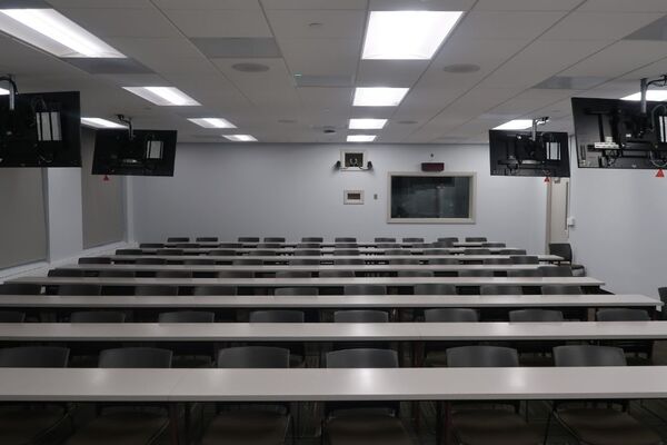 Back of room view of student table and chair seating and exit door at rear right of room