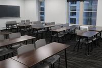 Back of room view of student table and chair seating and chalkboard on rear wall