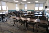 Back of room view of student table and chair seating and markerboards on right side wall