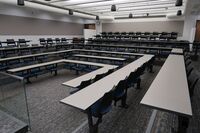 Back of room view of student fixed table and chair seating and exit doors at rear of room