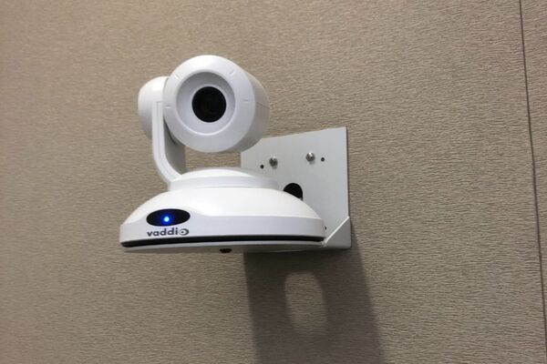 Camera mounted to a wall and instructor enabled adjustments to the lens to allow the instructor to be "seen" by the camera in more locations around the room