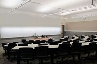 Front of room view with lectern center in front of markerboard and exit door at front right