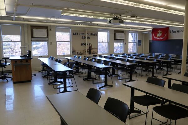 Back of room view of student table and chair seating and chalkboard on rear wall of room