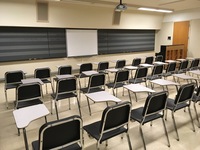 Photo of front of room from back of room with music staff chalkboard and piano.