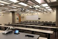 Back of room view of student table and chair seating and markerboard at rear of room