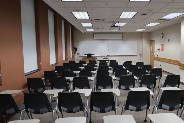 Front of room view with lectern on left in front of markerboard and projection screen partially raised