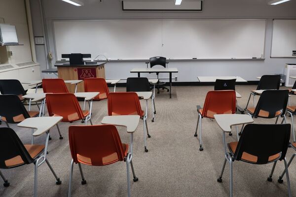 Front of room view with lectern on left in front of markerboard and projection screen partially raised