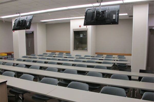 Back of room view of student fixed table and chair seating and exit doors at rear of room