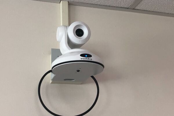 Camera mounted to a wall and instructor enabled adjustments to the lens to allow the instructor to be "seen" by the camera in more locations around the room