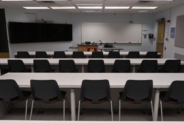 Front of room view with lectern center in front of markerboard, display monitor right, and exit door front right