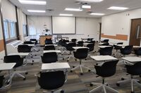  Front of room view with lectern on left in front of markerboard and projection screen lowered