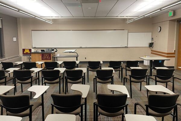 Front of room view with lectern on left in front of markerboard and exit door on the right